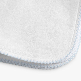 Close-up of a white textured fabric with blue stitching on a white background