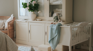 Nursery room with a white crib, dresser, and decorative items.