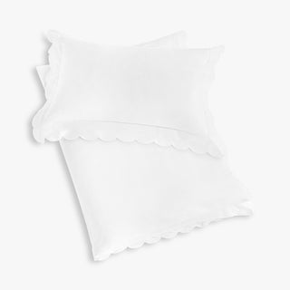 White pillow with scalloped edges on a folded toddler duvet.