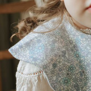 Winglet Bib- Enchanted Wildflower in Ivory close up shot on toddler girl