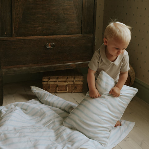 Baby holding Toddler Pillow in Coastal Stripes in the Blue Colorway