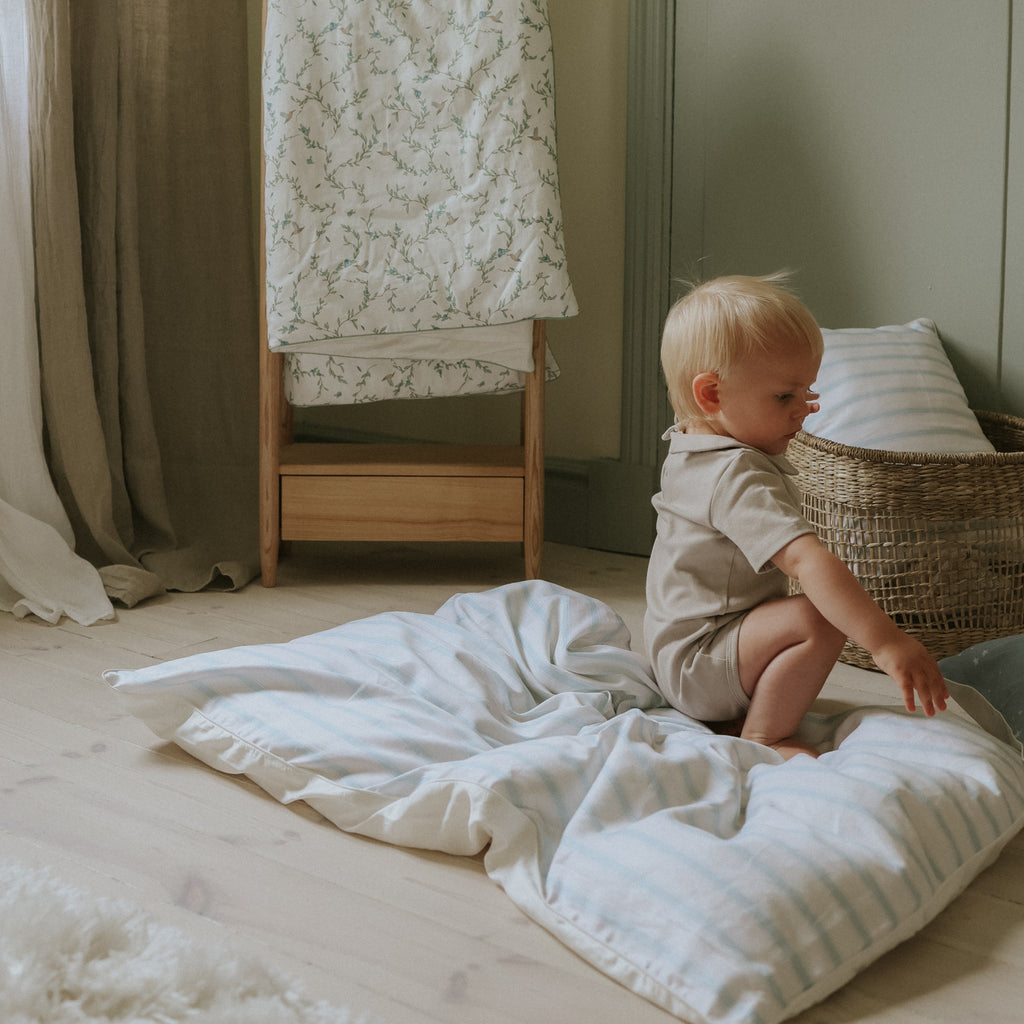 Baby Sitting on top of the Baby Duvet in the Coastal Print in Blue