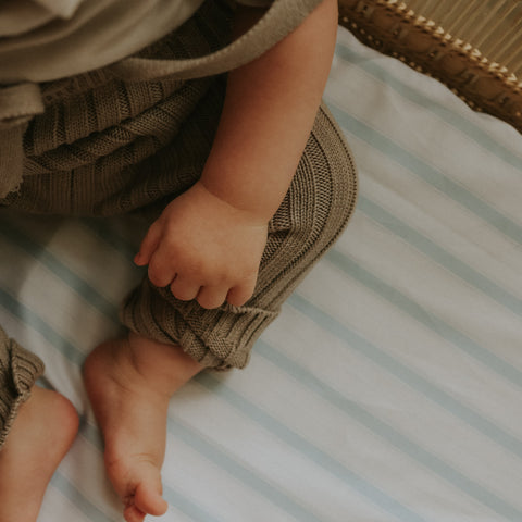 Blue Stripe Crib Sheet in a bassinet with a baby laying on top