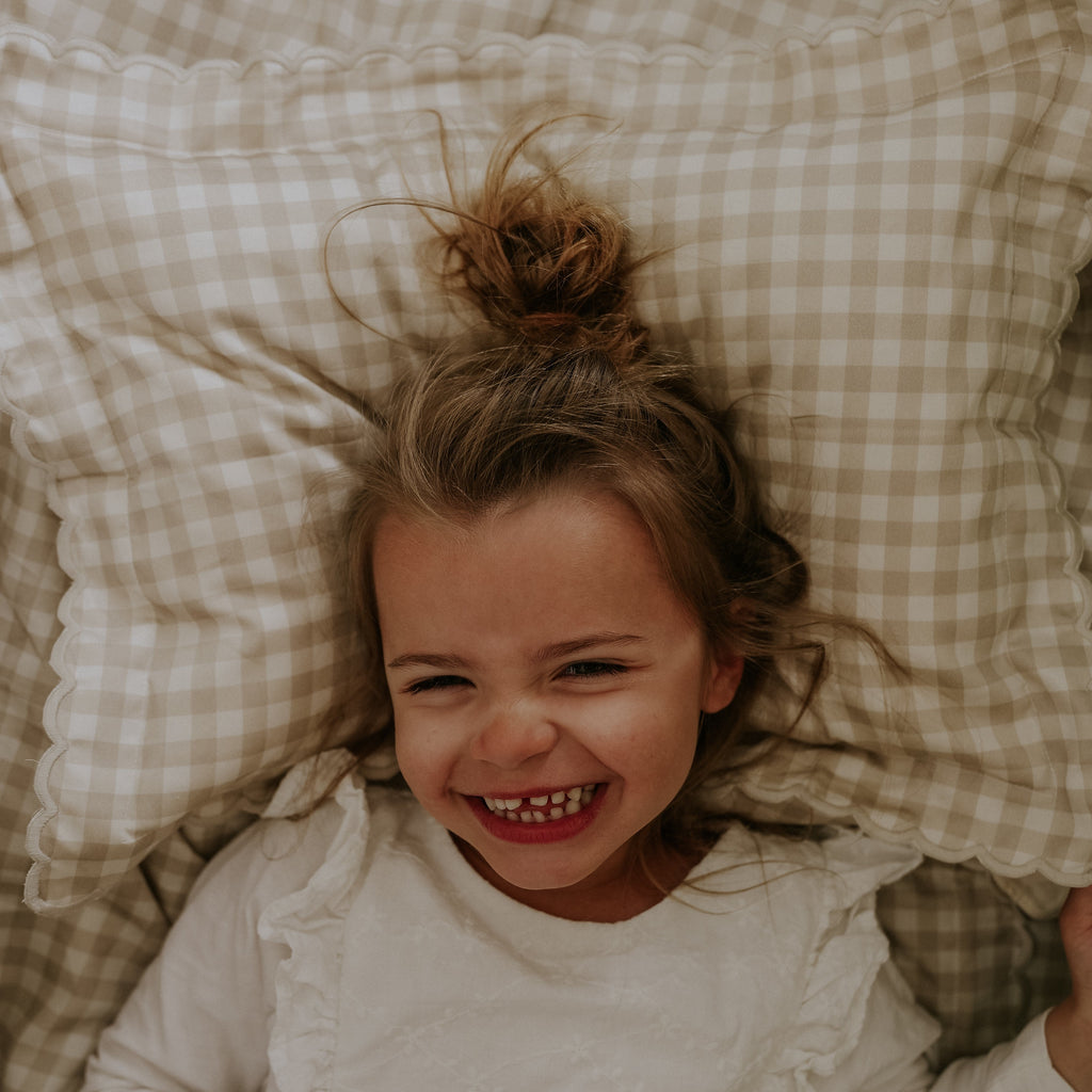 Toddler laying on top of the Toddler Pillow in Picnic Gingham Print in Beige Color