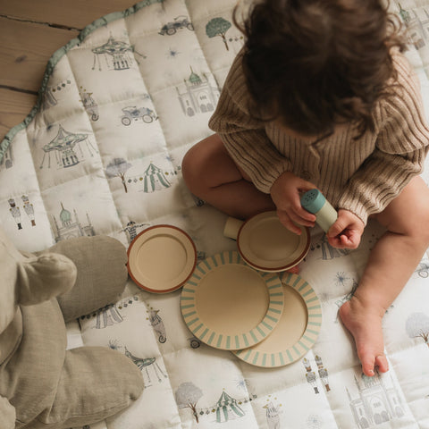 Adventures in wonderland playmat in Aqua with child playing on top with plates and stuffed animal