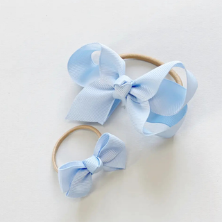 two blue bows with elastic headband on a beige background