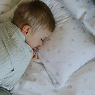 Child sleeping on a floral-patterned pillow and blanket