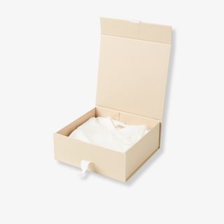 Beige cardboard box with a white baby onesie  inside on a light gray background