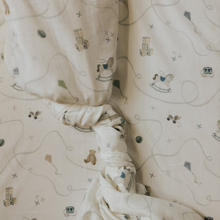 Baby swaddle on a crib sheet with toy prints on a crib