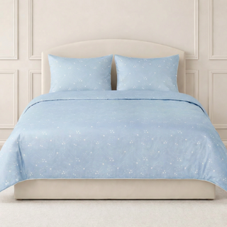 Blue star-patterned bedding set on a bed with a beige headboard.