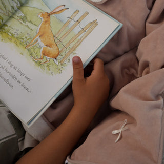 Child reading a book with the soft pink blanket