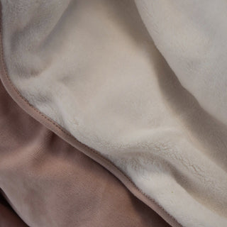 Close-up of a plush fleece blanket with a cream sherpa lining and a dusty pink velvet 