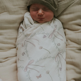 Newborn baby wrapped in a floral blanket on a soft surface