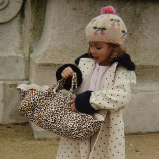 Little girl holding a leopard print doll bassinet.