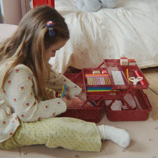 Child playing with an art caddy on the floor in a bedroom