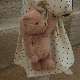Little girl in a polka dot coat carrying a bear shaped purse.