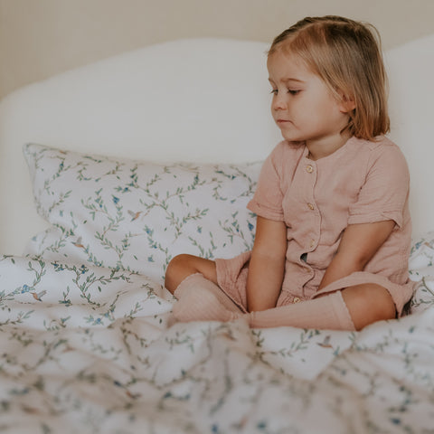 Toddler relaxing on the "Secret Garden" printed Twin Duvet Set wearing a pink outfit