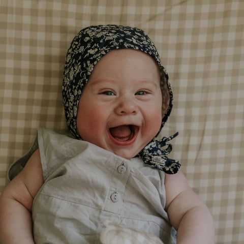 Baby Laying on top of Crib Sheet in the Beige color of the Picnic Gingham Print