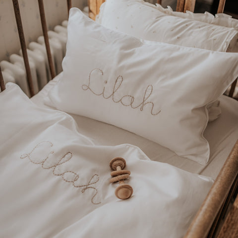 Lifestyle picture of the toddler pillow in the crib with the name Lilah written on it