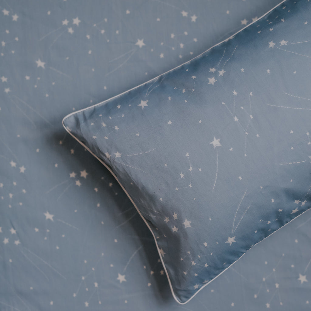 Toddler Pillow laying on top of Crib Sheet in the print "Once Upon A Time" in the color blue