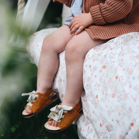 Toddler sitting on the gooseling duvet in the print "Into The Woodlands" in the color ivory