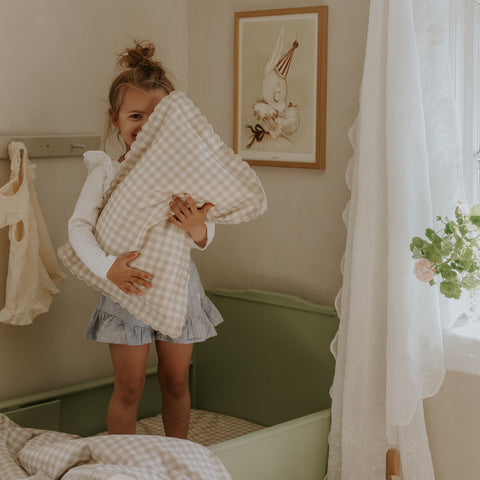 Toddler holding a toddler pillow in the Picnic Gingham Print in Beige