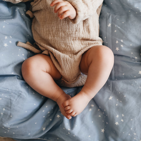 Baby laying on top of gooselings duvet in the print "Once Upon A Time" in color blue