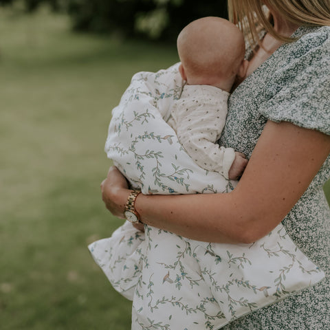 Baby in the arms of a mother, wrapped with the Baby Duvet in the print "Secret Garden" in the color ivory