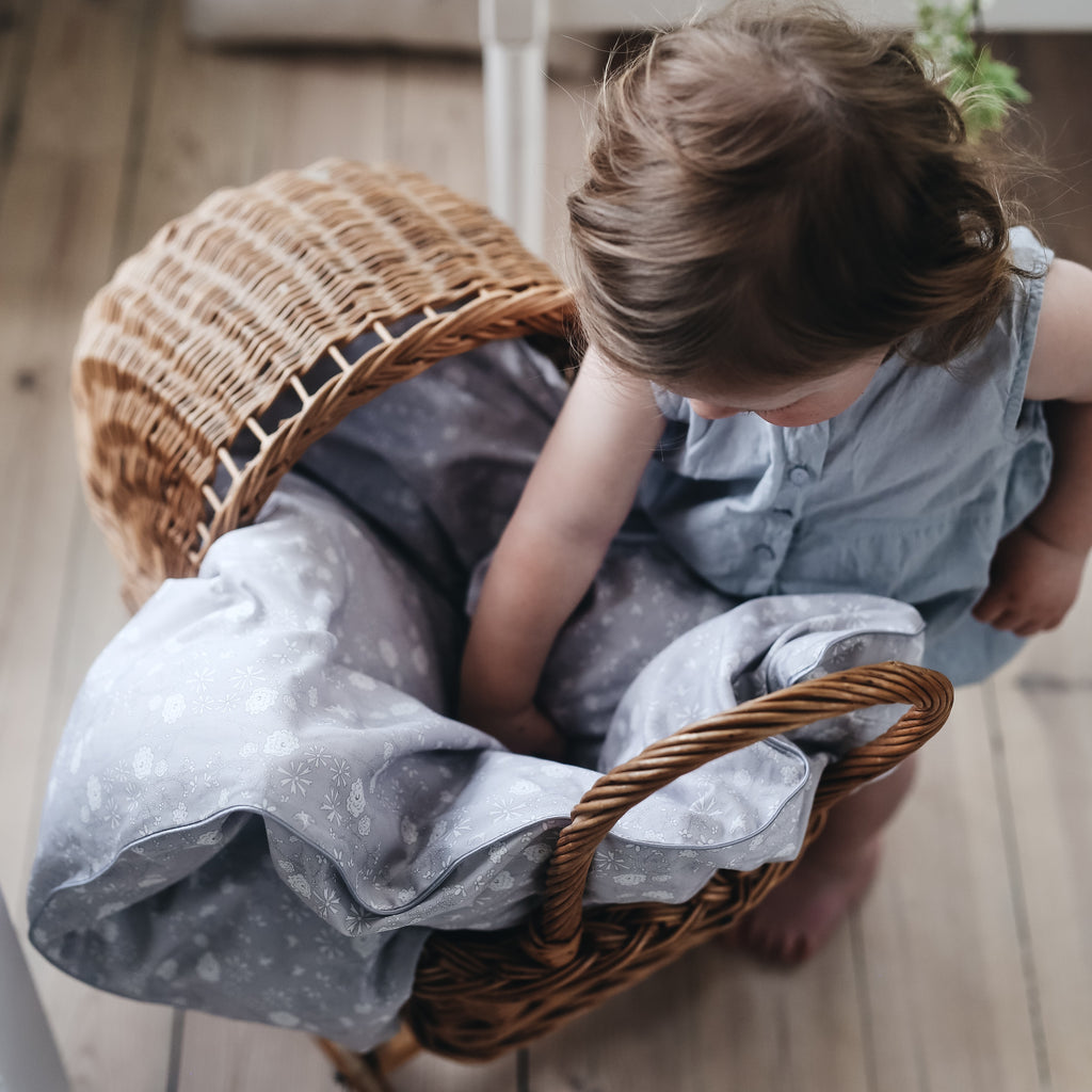 Toddler placing "Bird's Song" printed grey duvet in a toy carriage