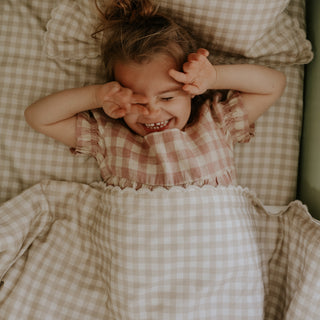 Toddler laying in bed with the Toddler Duvet in the Picnic Gingham Print in Beige