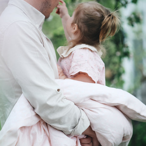 Dad hugging child wrapped in a gooselings baby duvet 