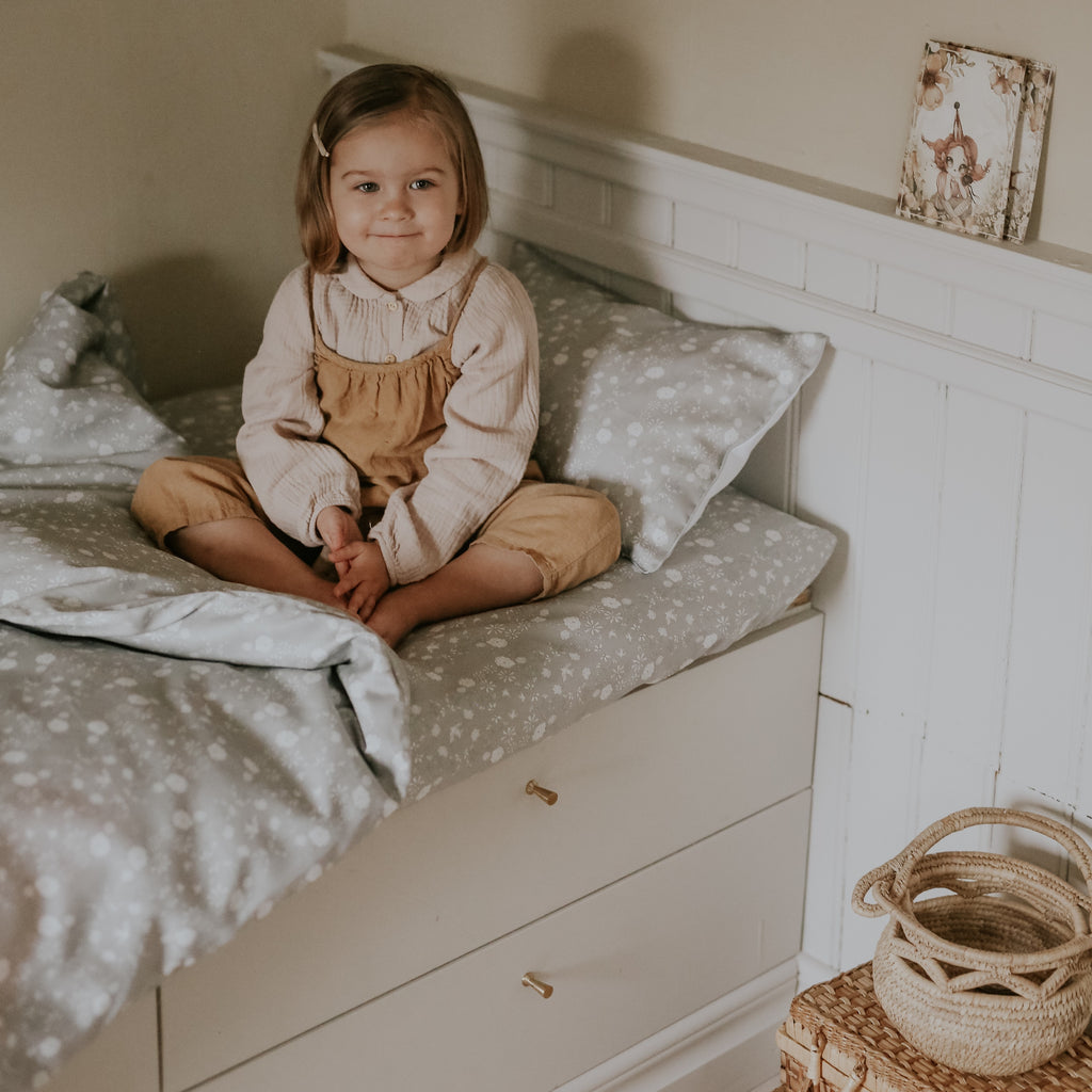 Toddler smiling in bed with gooselings duvet and toddler pillow